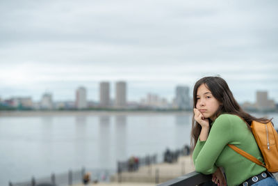 Portrait of young woman looking away against sky