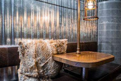 Fur cushion by illuminated table with sofa in espresso house at famous city