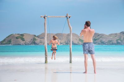 Man photographing woman on swing