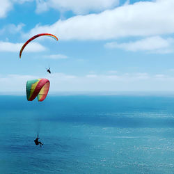 People paragliding over sea against sky
