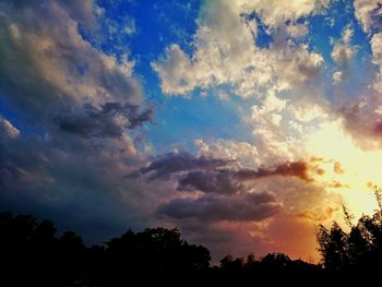 Low angle view of silhouette trees against dramatic sky