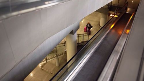 Woman standing on escalator