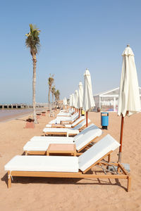 Lounge chairs by swimming pool at beach against clear sky