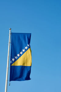 Low angle view of flag against clear blue sky