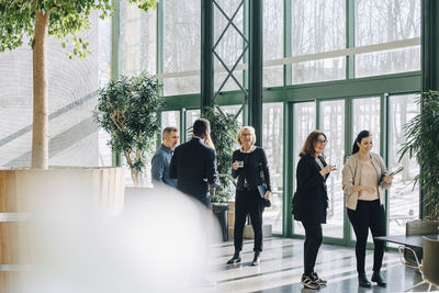 Full length of business people standing by window at office