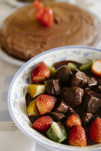 Fresh fruits and in bowl with chocolate on table with birthday cake