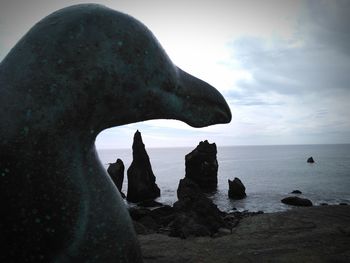 Rock formation by sea against sky