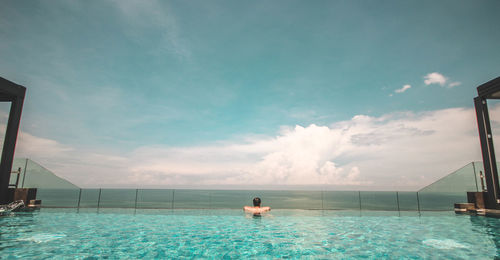 Rear view of shirtless man in infinity pool