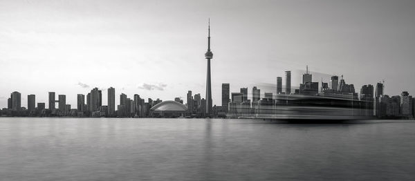 View of skyscrapers by lake against sky