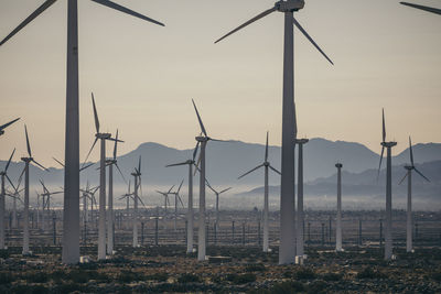 Windmills against sky during sunset