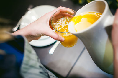 Cropped hands of woman pouring juice in drinking glass