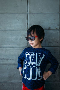 Boy with hands on hip standing against wall