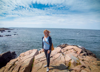 Full length of woman standing on rock against sea