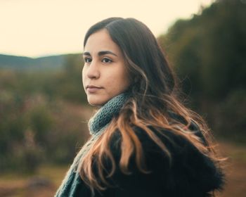 Young woman looking away against sky