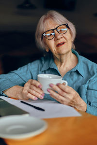 Portrait of woman using mobile phone while sitting at home