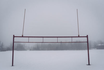 Goal post on snowfield against sky