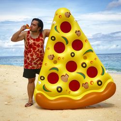 Man eating pizza with inflatable at beach against sky