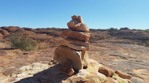 Stack of stones on landscape against clear sky