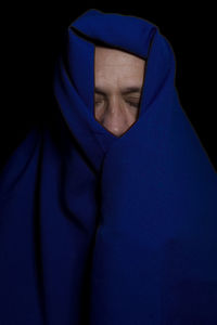 Man covered with blue cloth against a black background. salvador, bahia, brazil.