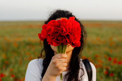 Woman with poppy bouquet covering face