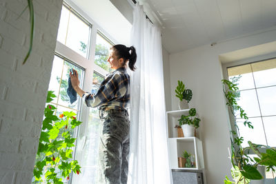 Side view of woman standing by window