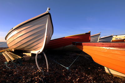 Boat moored on shore against clear blue sky