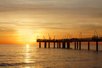 Pier on sea against sky during sunset