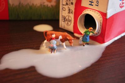 High angle view of figurines on spilled milk