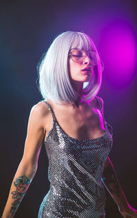 Woman in dress standing against black background