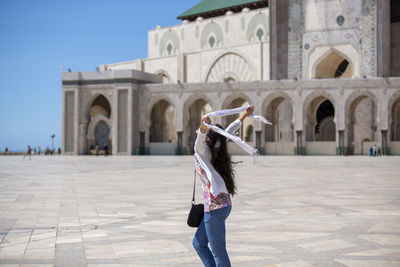 Woman in floral shirt enjoying the breeze at an islamic mosque's courtyard.