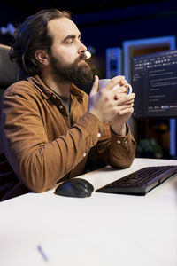 Side view of man using mobile phone while sitting on table