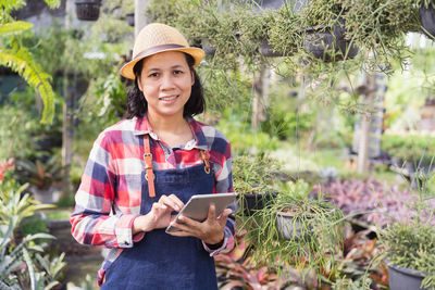 Portrait of smiling young woman using mobile phone outdoors