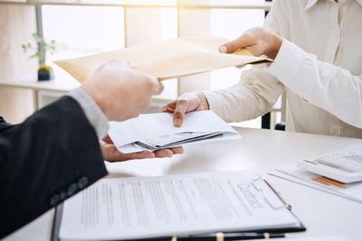 Cropped image of business people exchanging envelopes