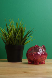 Close-up of coins in piggy bank with potted plant on table