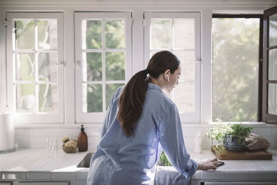 Woman standing by window at home