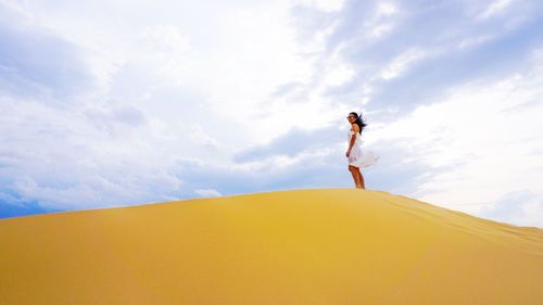 Woman standing at beach against sky