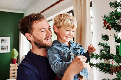 Father and son touching christmas tree at home