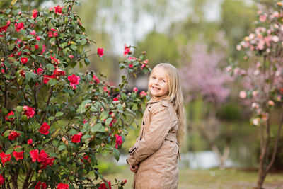 Portrait of young woman standing against plants