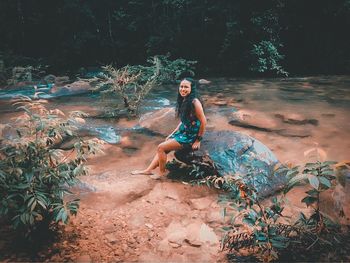 Full length portrait of young woman sitting on land