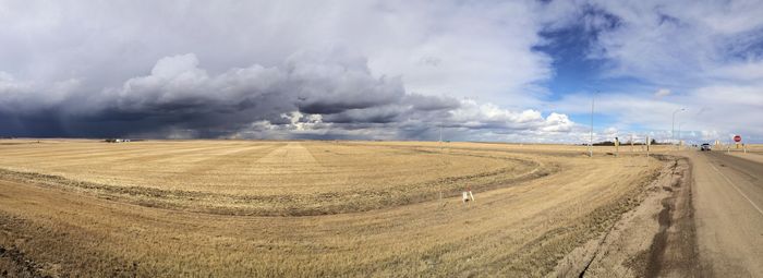 Panoramic view of field against cloudy sky