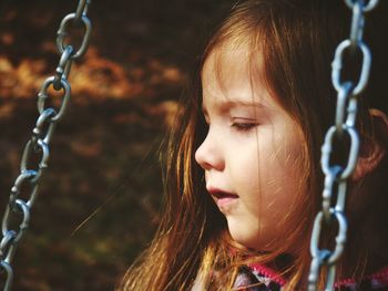 Close-up of cute girl swinging at playground