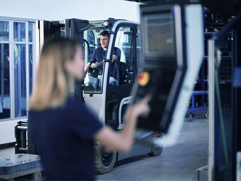 Blue-collar worker riding forklift in factory