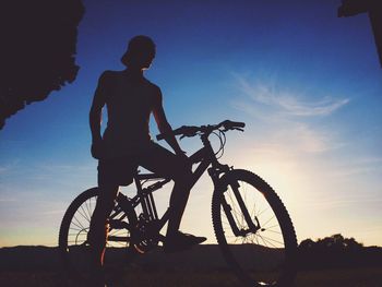 Silhouette of man with bicycle at sunset