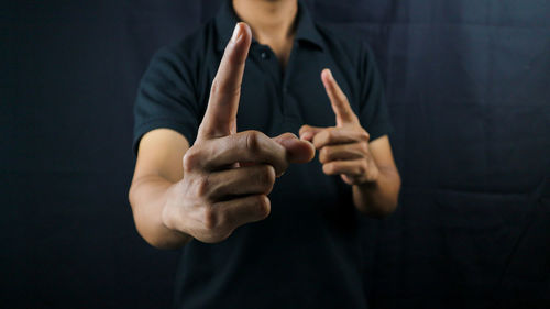 Midsection of man gesturing against black background