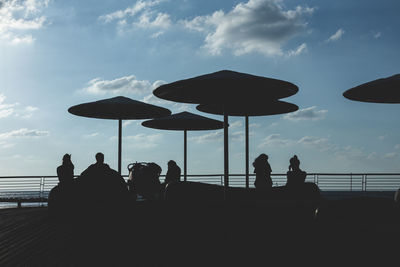 Silhouette people by sea against sky