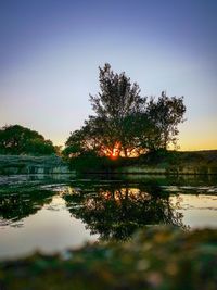 Scenic view of lake against clear sky at sunset