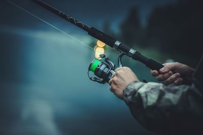 Cropped hands of man holding fishing rod