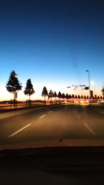 Road by trees against clear sky seen through car windshield