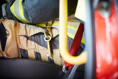 Midsection of firefighter with key ring sitting in fire truck