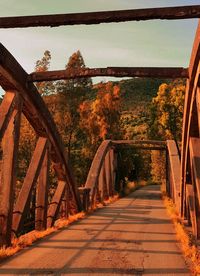 Empty bridge over river against sky